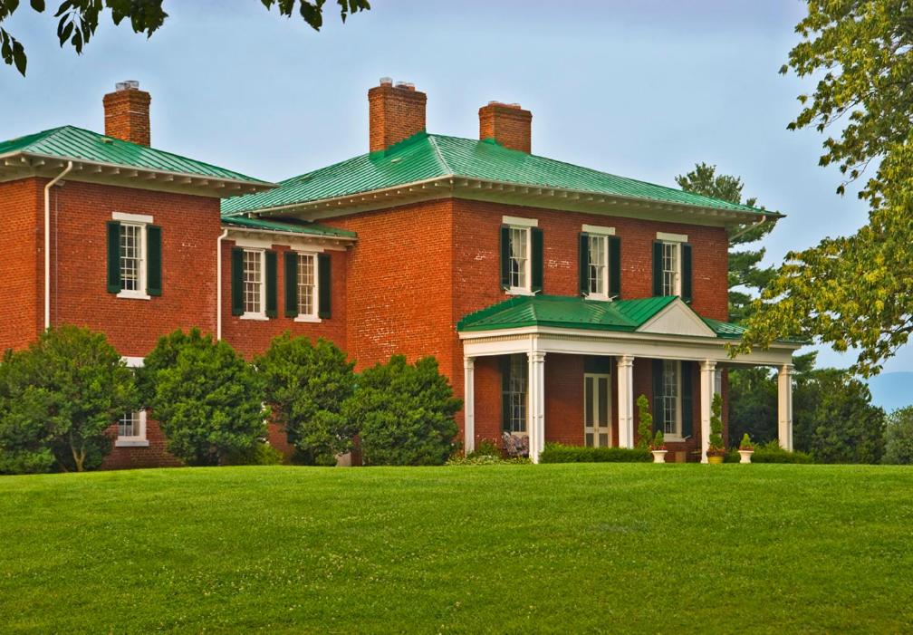 uma grande casa de tijolos vermelhos com um telhado verde em Marriott Ranch Bed and Breakfast em Hume