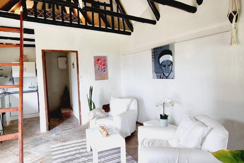 una sala de estar con 2 sofás blancos y una escalera en The Loft: Cosy 1 Bed Loft W/ Amazing View and Pool, en Bothaʼs Hill