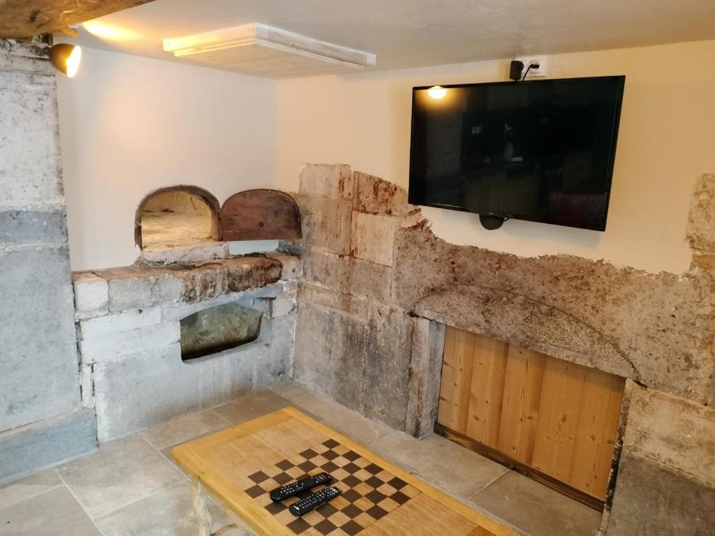 um quarto com televisão e um tabuleiro de xadrez no chão em ô Doux Comtois em Les Fourgs