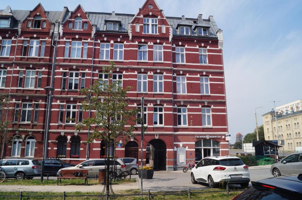 un edificio de ladrillo rojo con coches aparcados delante de él en Przestronne mieszkanie w centrum Gdańska en Gdansk