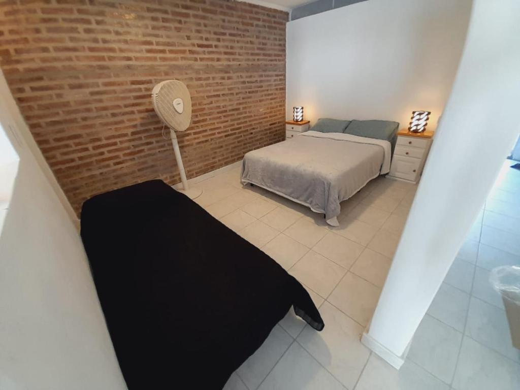 een slaapkamer met een bed en een bakstenen muur bij Alquiler por día General Villegas in General Villegas