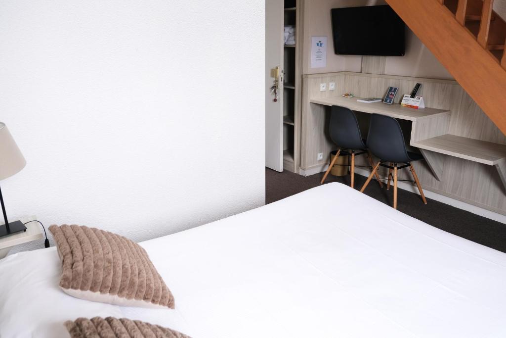 a bedroom with a bed and a desk and two chairs at Hôtel Arcadia in Lannion