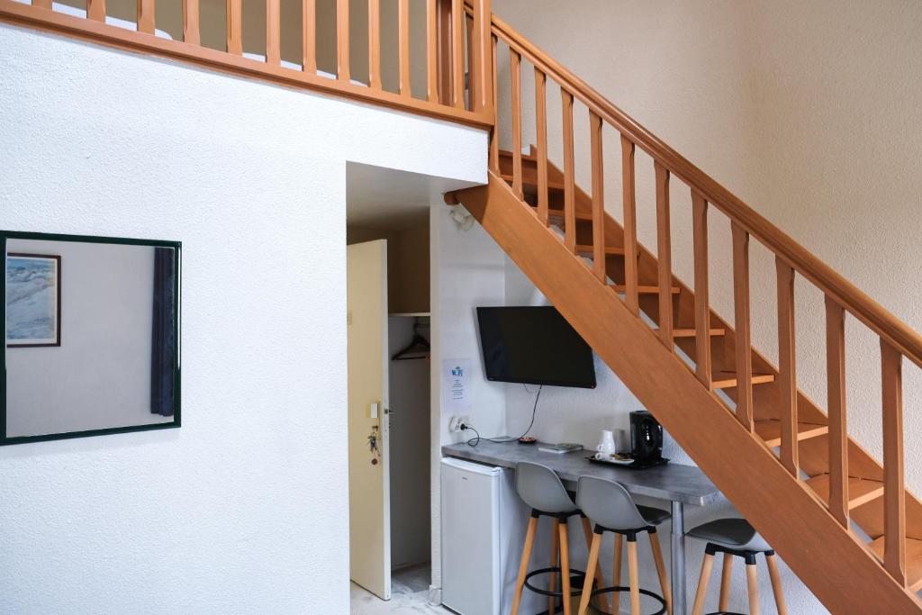 a room with a desk with a computer and a staircase at Hôtel Arcadia in Lannion