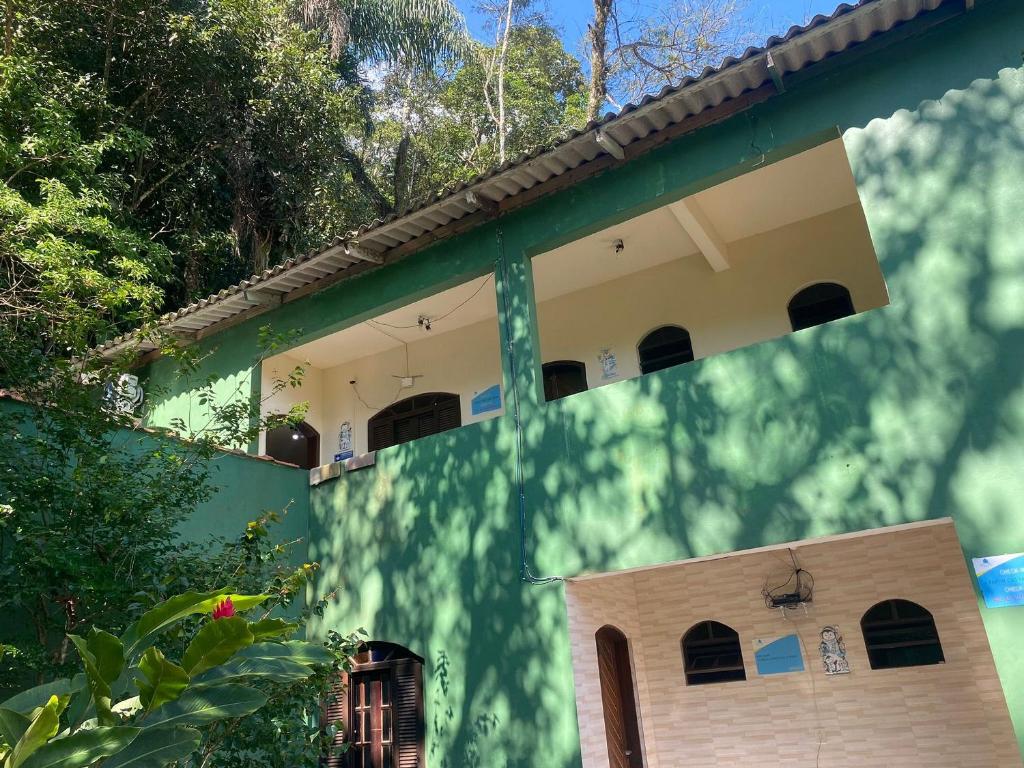 une maison avec un mur vert et blanc dans l'établissement Boca da Lagoa - Onde o Sol, o Mar e a Montanha se Encontram, à Boicucanga