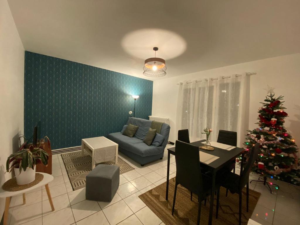 a living room with a christmas tree and a blue couch at Appartement cosy près de la gare avec parking in Saint-Pierre-des-Corps