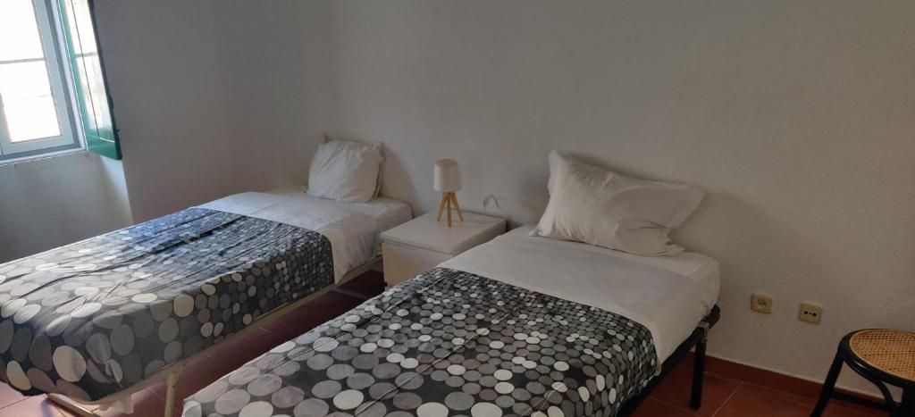 sypialnia z 2 łóżkami, krzesłem i oknem w obiekcie Casa da Cal Branca w mieście Évora