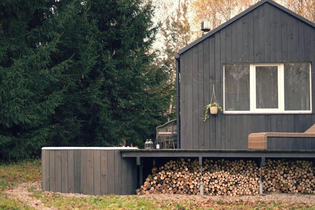 una casa negra con una pila de leña en Hand made Off Grid forest Cabin Luna 