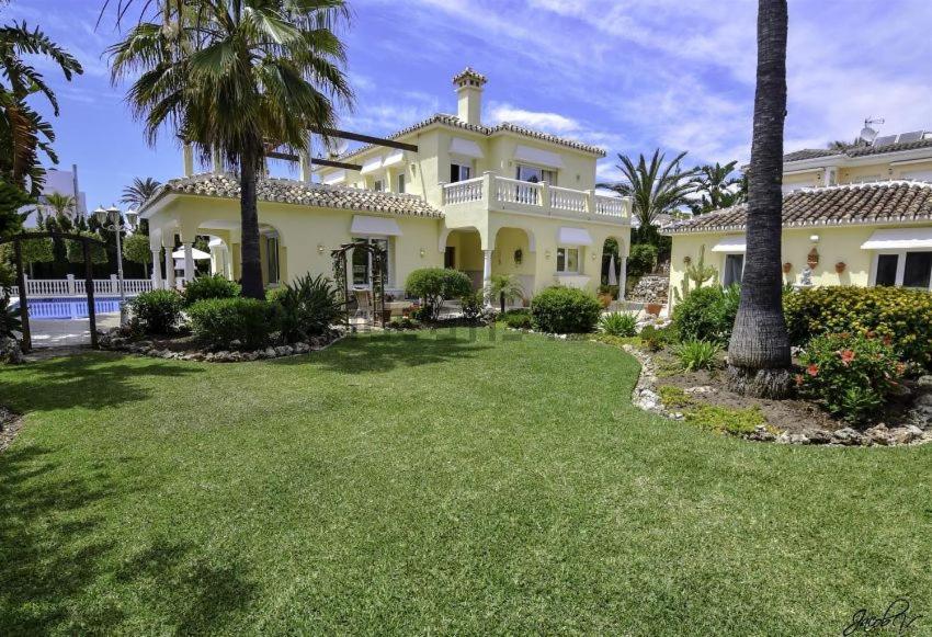 ein großes weißes Haus mit Palmen und einem Hof in der Unterkunft Beautiful villa 2 steps from the BEACH in Marbella