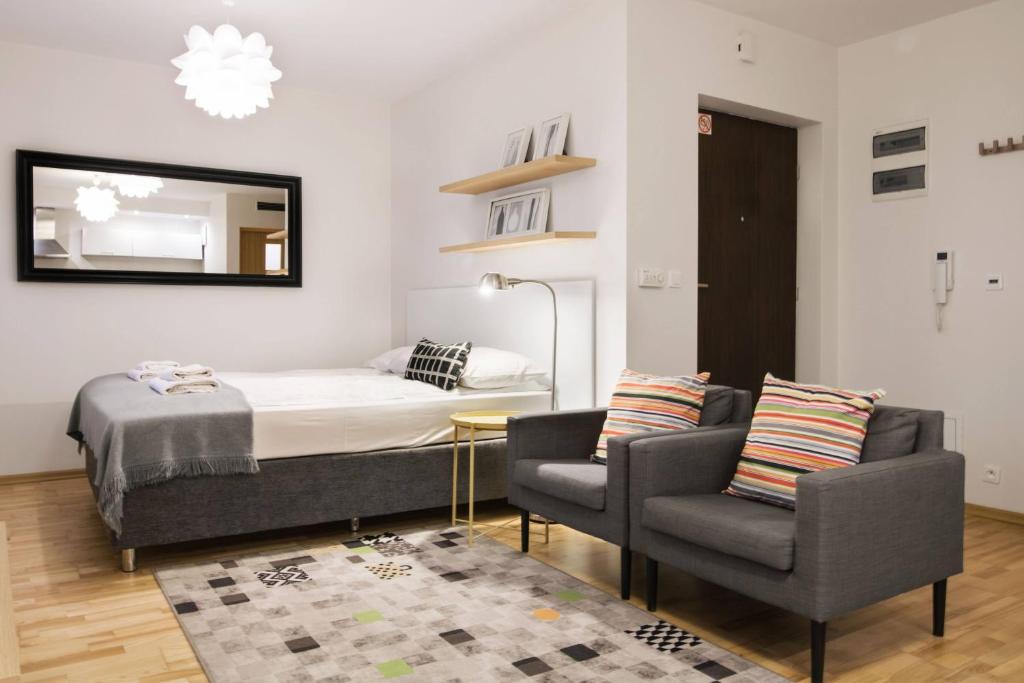 a bedroom with a bed and two chairs and a mirror at Yourplace Central Apartments in Kraków