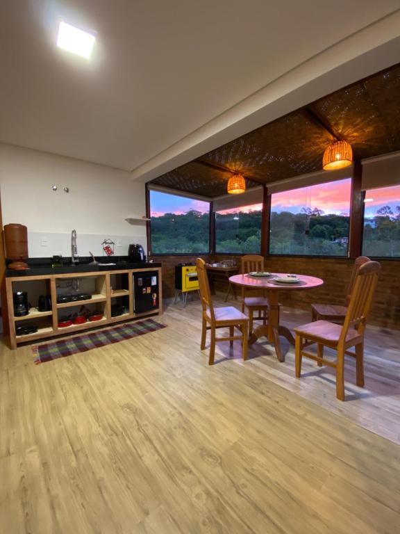 een woonkamer met een tafel, stoelen en ramen bij CHALÉS SÓ COISAS BOAS in Ouro Preto