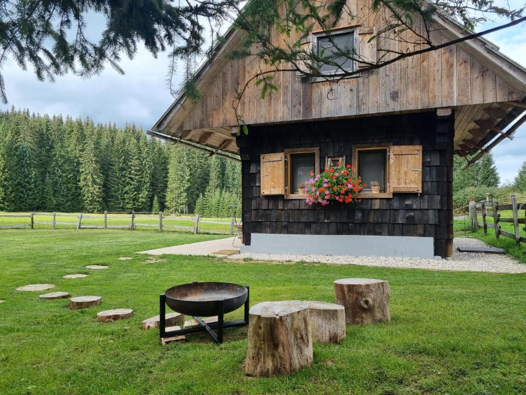 a barn with a bench and logs in the grass at Zalin planinski raj in Goreljek