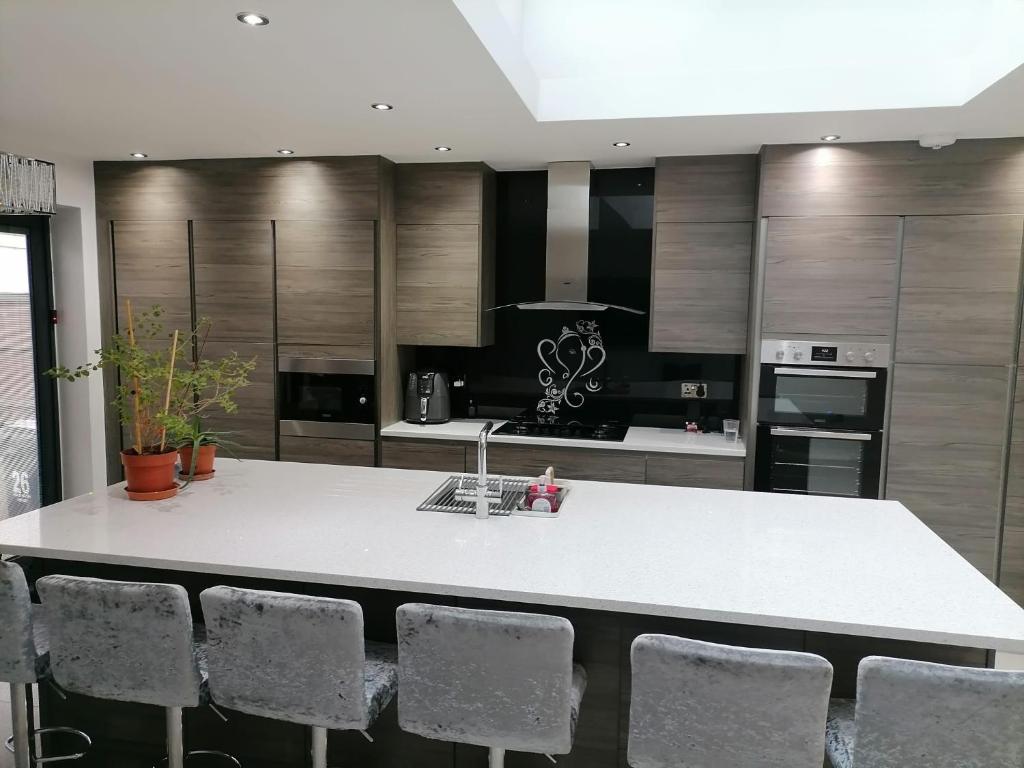una cocina con encimera blanca y sillas. en Grand 4 Bed 3 Bath House Chadwell Heath, Romford, London en Goodmayes