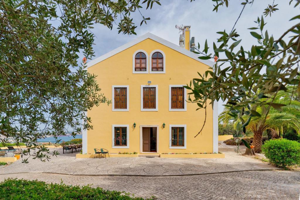 een geel huis met een wit dak bij Villa Casal Assis in Setúbal