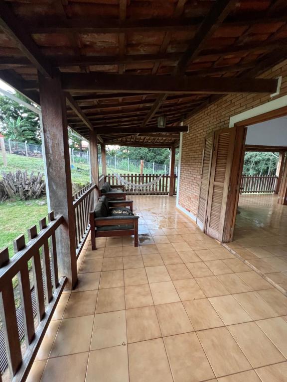 un gran porche con techo de madera y un banco. en Casa de Campo do Caminho da Fé en Águas da Prata