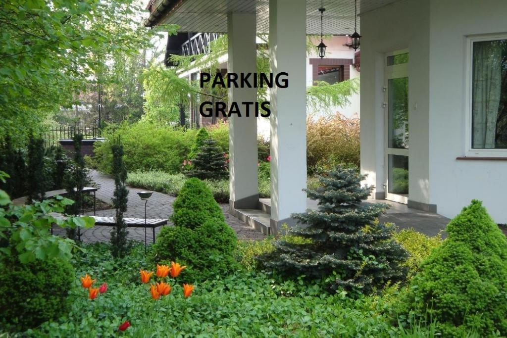 un jardin avec un panneau indiquant les objets de stationnement dans l'établissement Hotel Flora, à Łódź