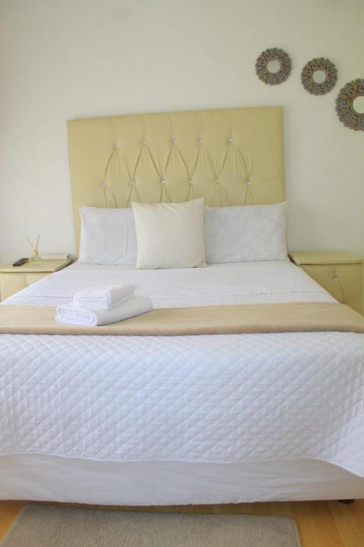 a large white bed with two towels on it at El Rose Guest House in Rustenburg
