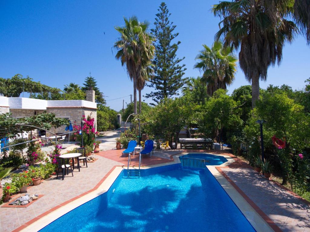 a swimming pool with palm trees in the background at Maros Spitaki in Varípetron