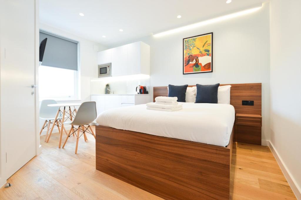 a bedroom with a large bed and a kitchen at West Hampstead Serviced Apartments in London