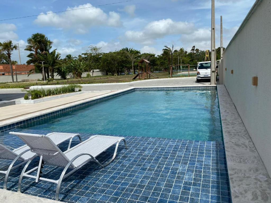 a swimming pool with two chairs and a swing at Lençóis Confort Barreirinhas in Barreirinhas