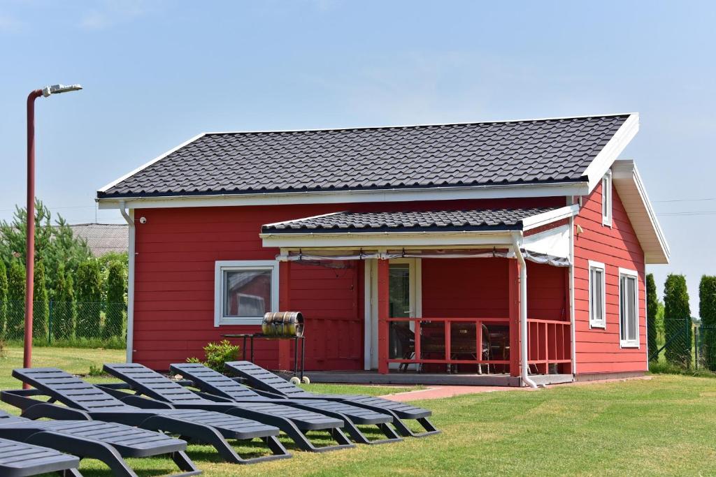 una casa roja con sillas delante en Villa Ievyne 2, en Paežeriai