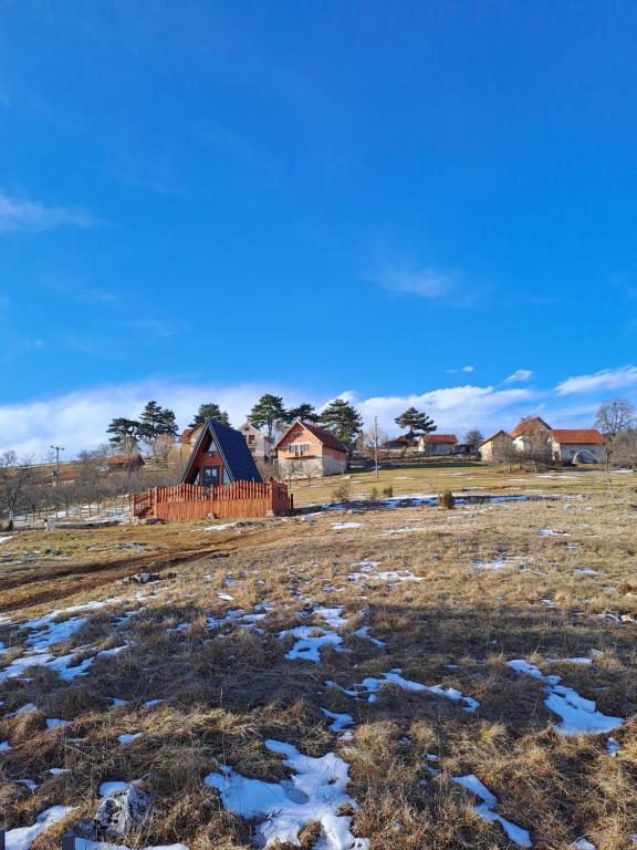 a field with snow in front of a house at A Pine vikendica u srcu Zapadne Srbije in Nova Varoš