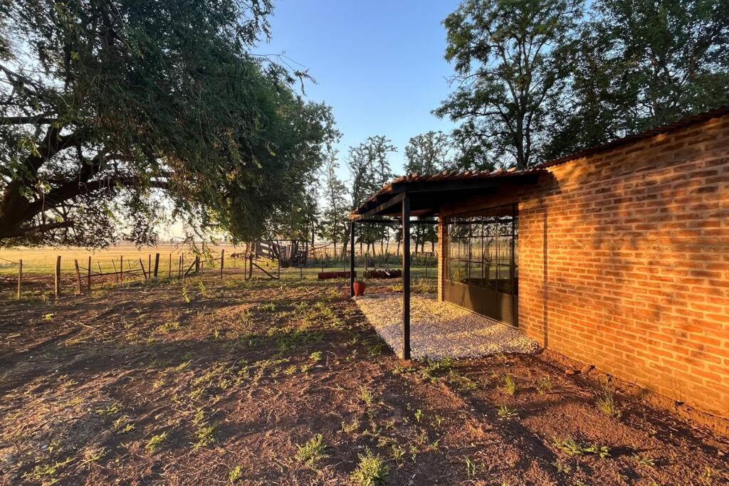 un edificio de ladrillo con un refugio en un campo en La Angelita en San Andrés de Giles