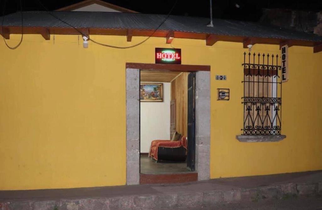 een geel gebouw met een neonbord erop bij Hotel del Ferrocarril in Quetzaltenango