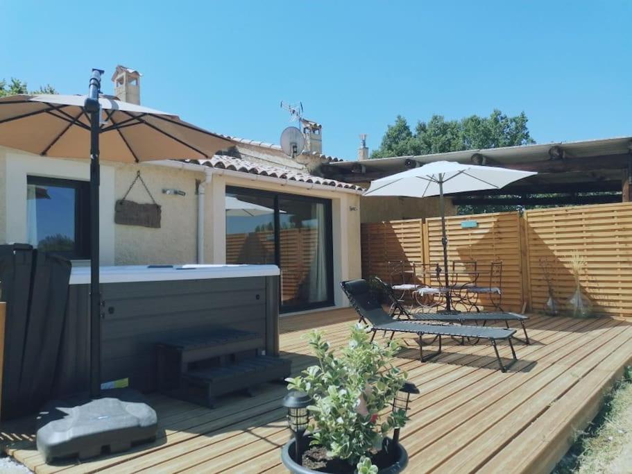 een houten terras met een bank en een parasol bij Gîte de charme SPA privatif in Malaucène