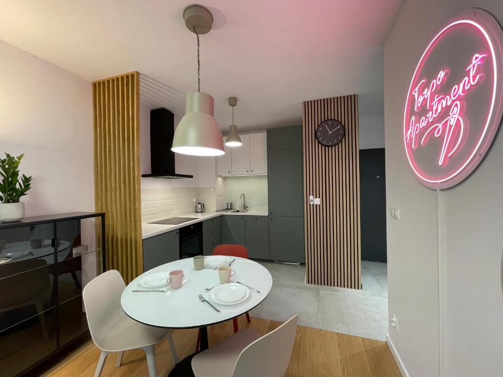 a white table with chairs and a pink neon sign at Torpo Apartment with parking in Toruń
