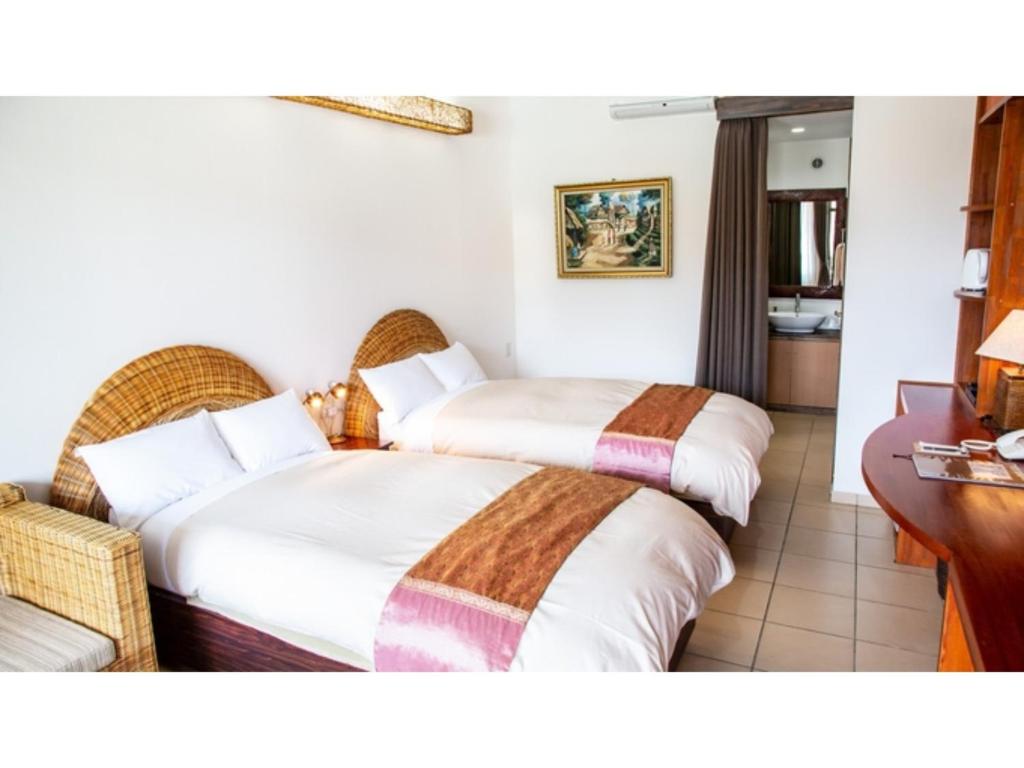 um quarto de hotel com duas camas e uma secretária em Hachijojima Hotel Resort Sea Pillows - Vacation STAY 53160v em Mitsune