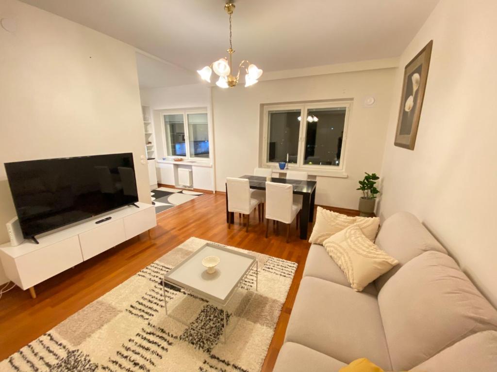 sala de estar con sofá blanco y TV de pantalla plana en Family city apartment Helsinki en Helsinki