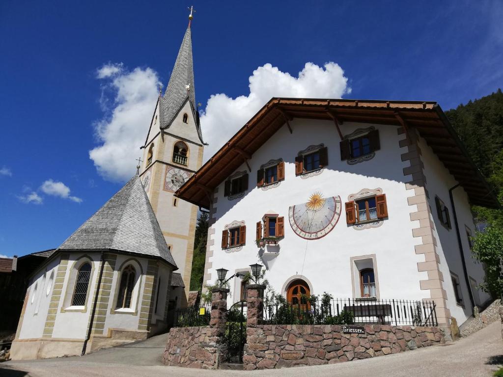 a large white building with a clock tower at Gosthof Kastelruth in Castelrotto