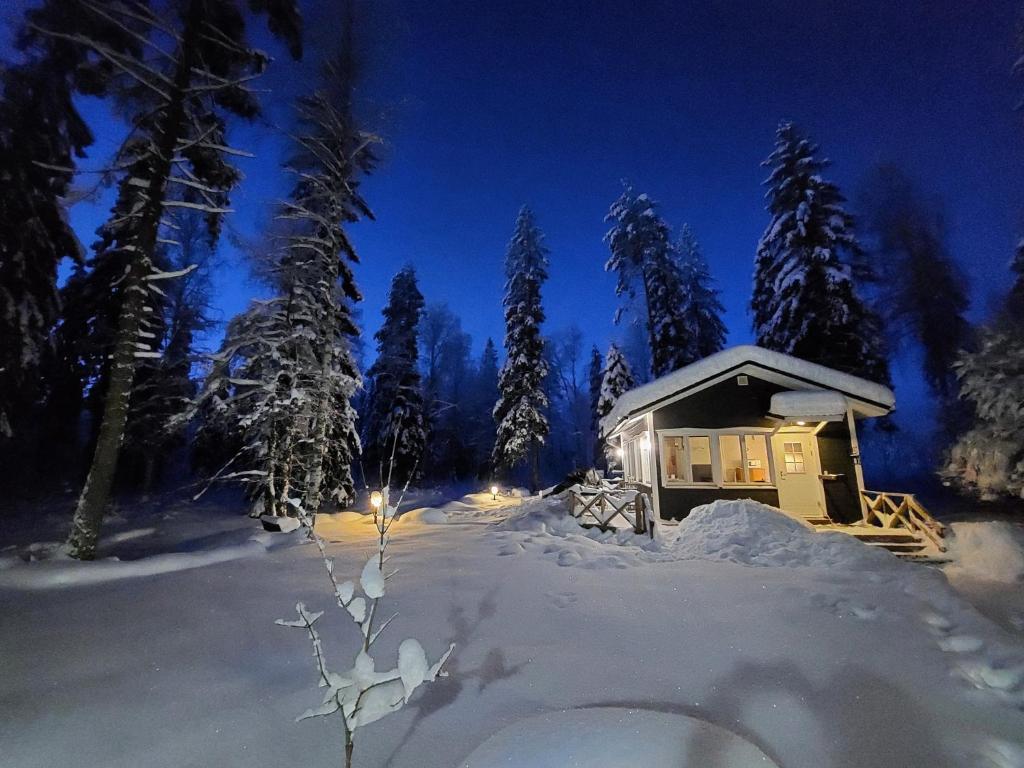 una cabina nella neve di notte di Venejoen Piilo - Kuohu a Kontiolahti