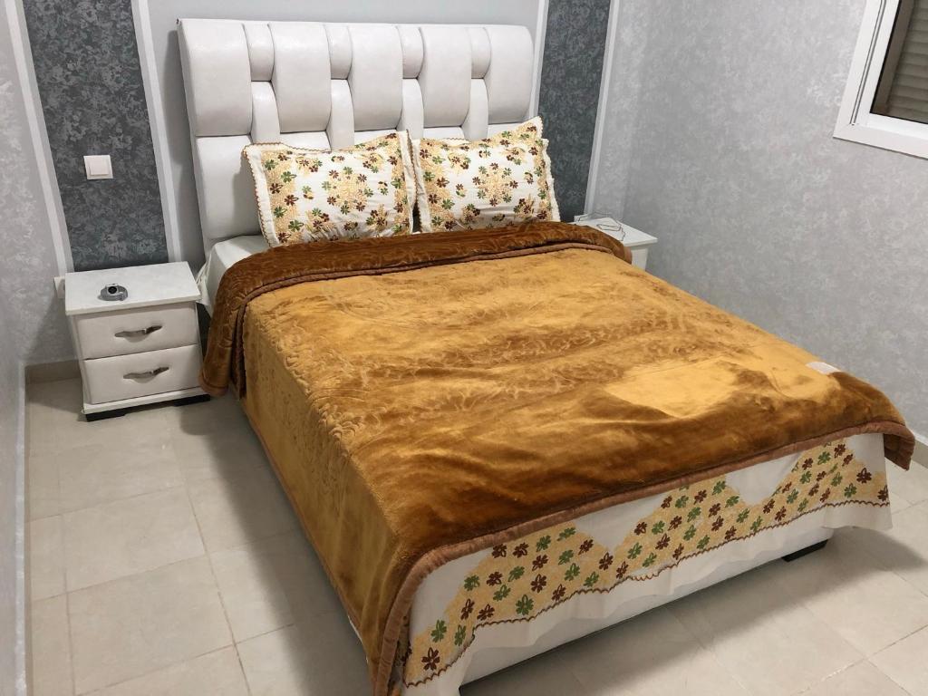 a bedroom with a large bed with a white headboard at Petit appartement très chaleureux à 1 minute de marche du stade de Tanger(Ibn Batouta) in Tangier
