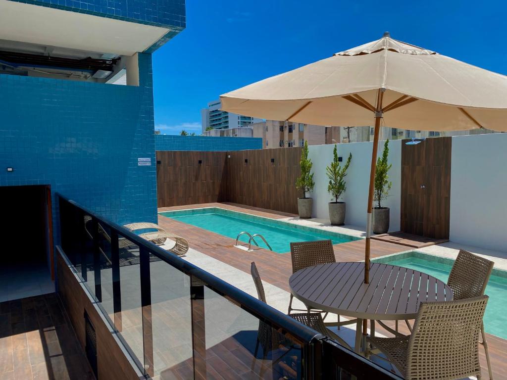 una mesa con sombrilla junto a la piscina en Vista Mar com 2 quartos, en Maceió