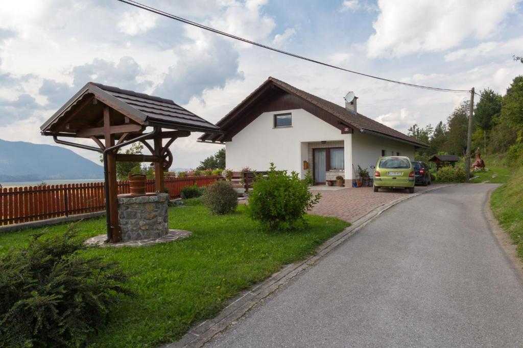 uma casa branca com um gazebo ao lado de uma estrada em Prenočišča Jezero em Gorenje Jezero