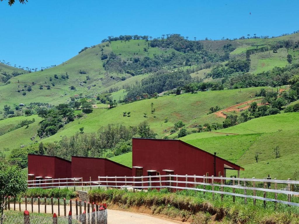 un granero rojo al lado de una colina en La Trinca Casas Charmosas en São Bento do Sapucaí