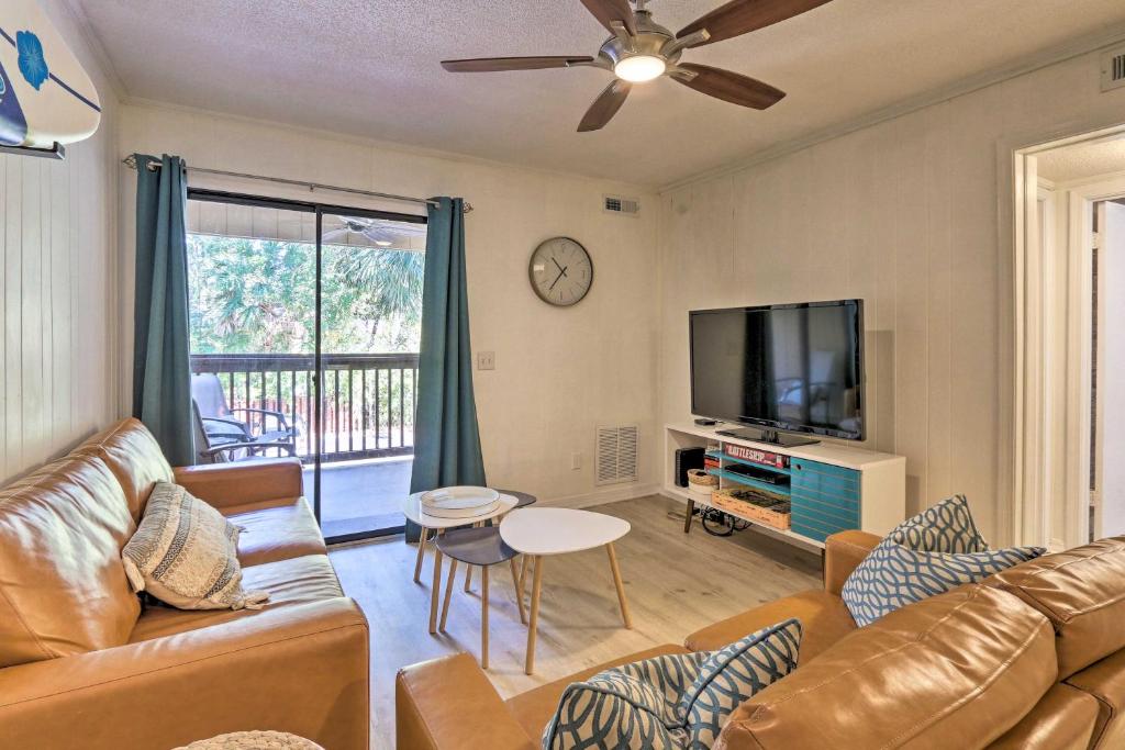 a living room with a couch and a flat screen tv at Hilton Head Condo with Shared Pool - Walk to Beach! in Hilton Head Island