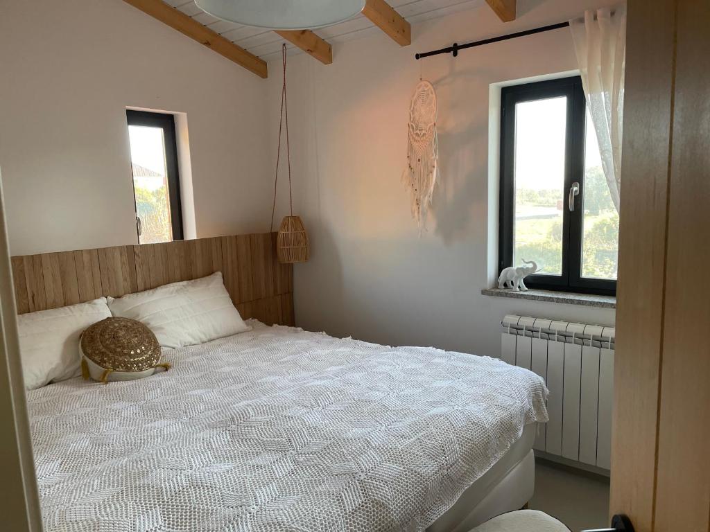 a bedroom with a white bed and two windows at Casinha Revira Volta in Nesperal