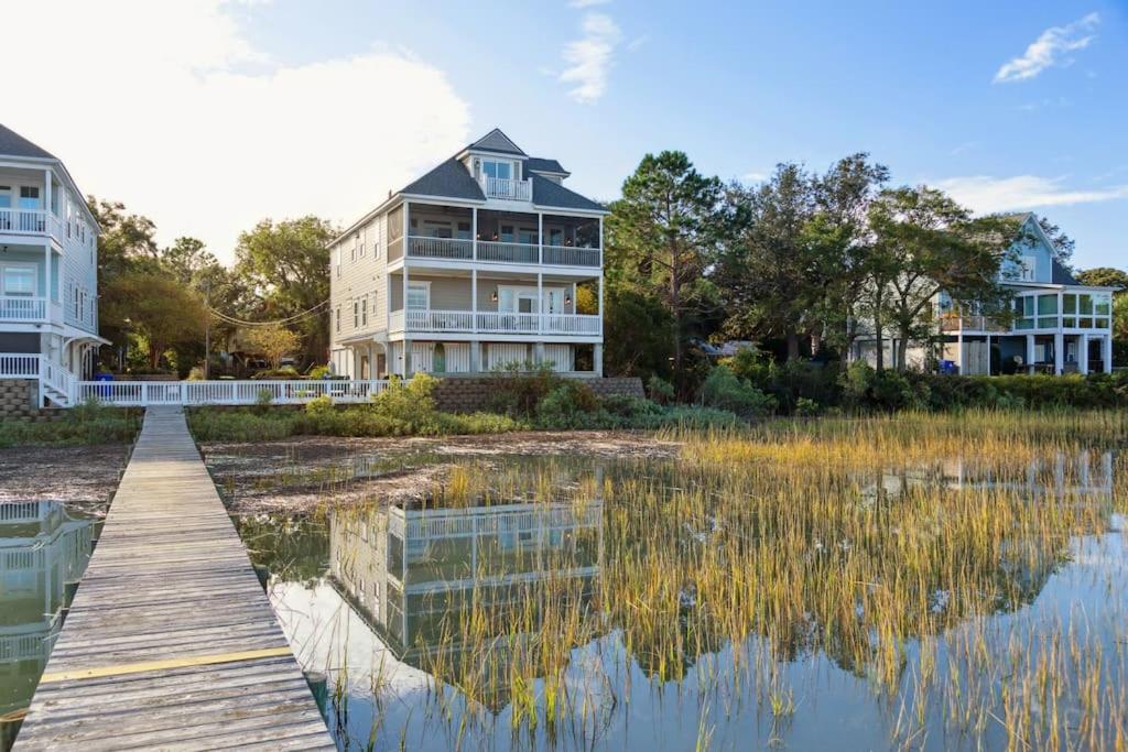 a house next to a body of water with a dock at 616 E Erie Driftwood Marsh and River Views Private Pool in Folly Beach