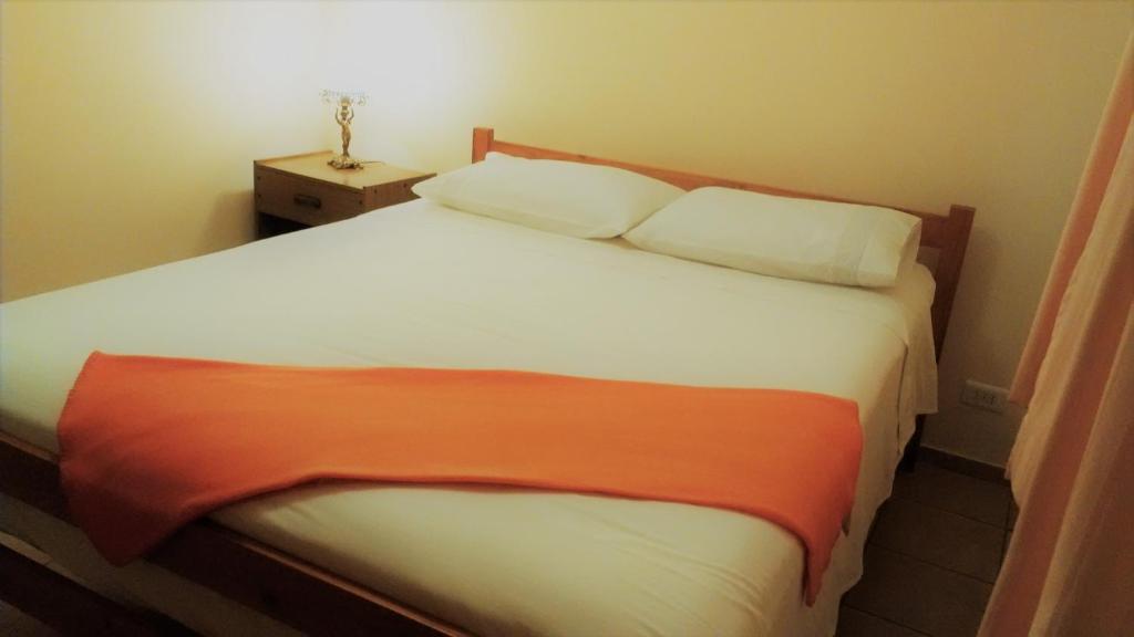 1 dormitorio con cama blanca y manta naranja en Full Equipada La Herradura, en Coquimbo