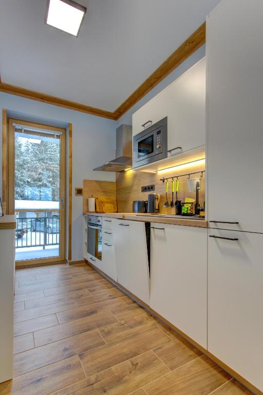 a kitchen with white appliances and a wooden floor at Rezidence KUPEC in Frymburk