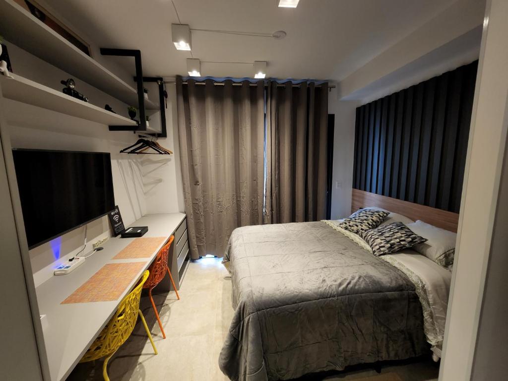 een slaapkamer met een bed, een bureau en een televisie bij Studio SP ao lado Shopping Frei Caneca in Sao Paulo