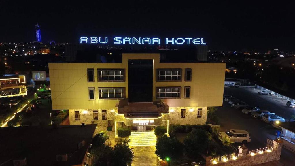 um edifício com um sinal em cima dele à noite em Abu Sanaa Hotel em As Sulaymānīyah