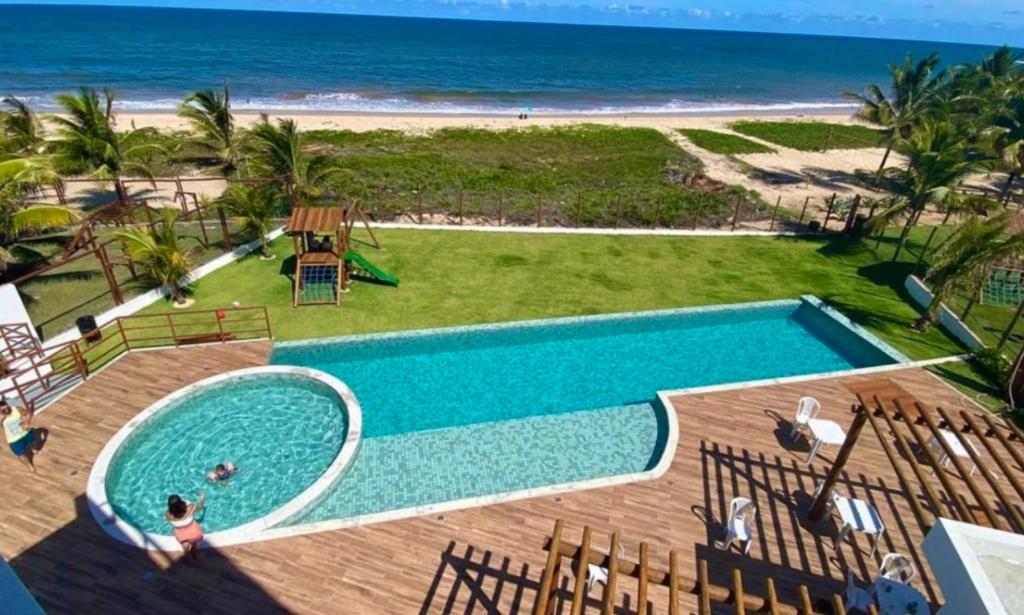 a swimming pool with the beach in the background at Itacimirim pé na areia 2Q in Itacimirim