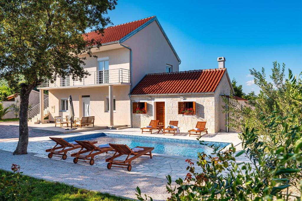 une villa avec une piscine en face d'une maison dans l'établissement MY DALMATIA - Holiday home Zara with private swimming pool, à Stankovci