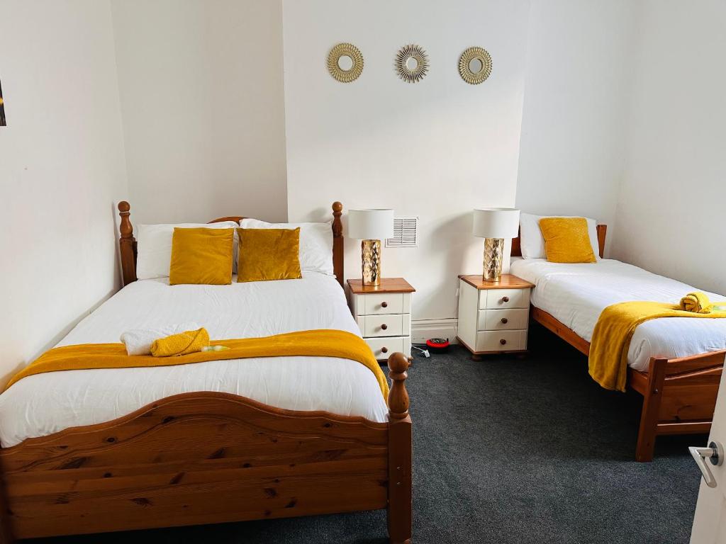 - une chambre avec 2 lits et des oreillers jaunes dans l'établissement Blessed Roker home with free parking., à Monkwearmouth