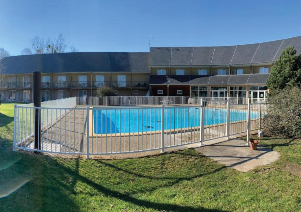 uma cerca em torno de uma piscina em frente a um edifício em Studio avec piscine aux portes d’Honfleur em Honfleur
