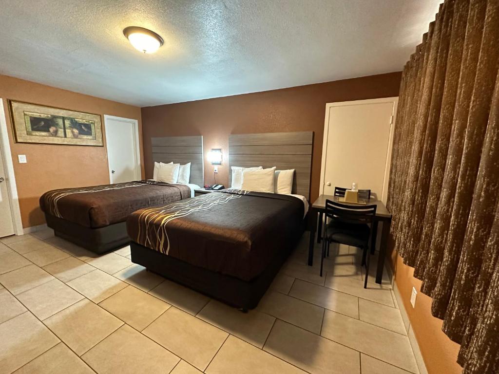Habitación de hotel con 2 camas y mesa en New Corral Motel en Victorville