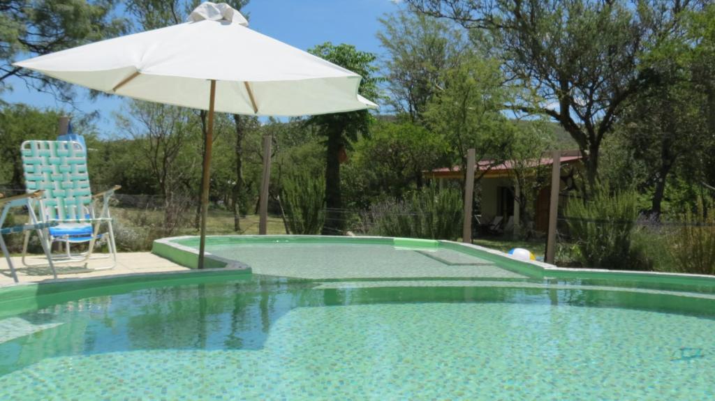 - Piscina con sombrilla, mesa y silla en Cabañas Entre Verde, en Los Hornillos